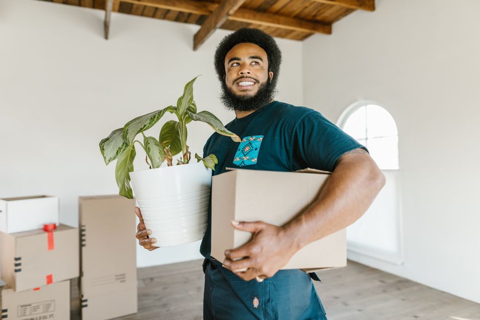 Smiling movers carrying boxes carefully out of a home